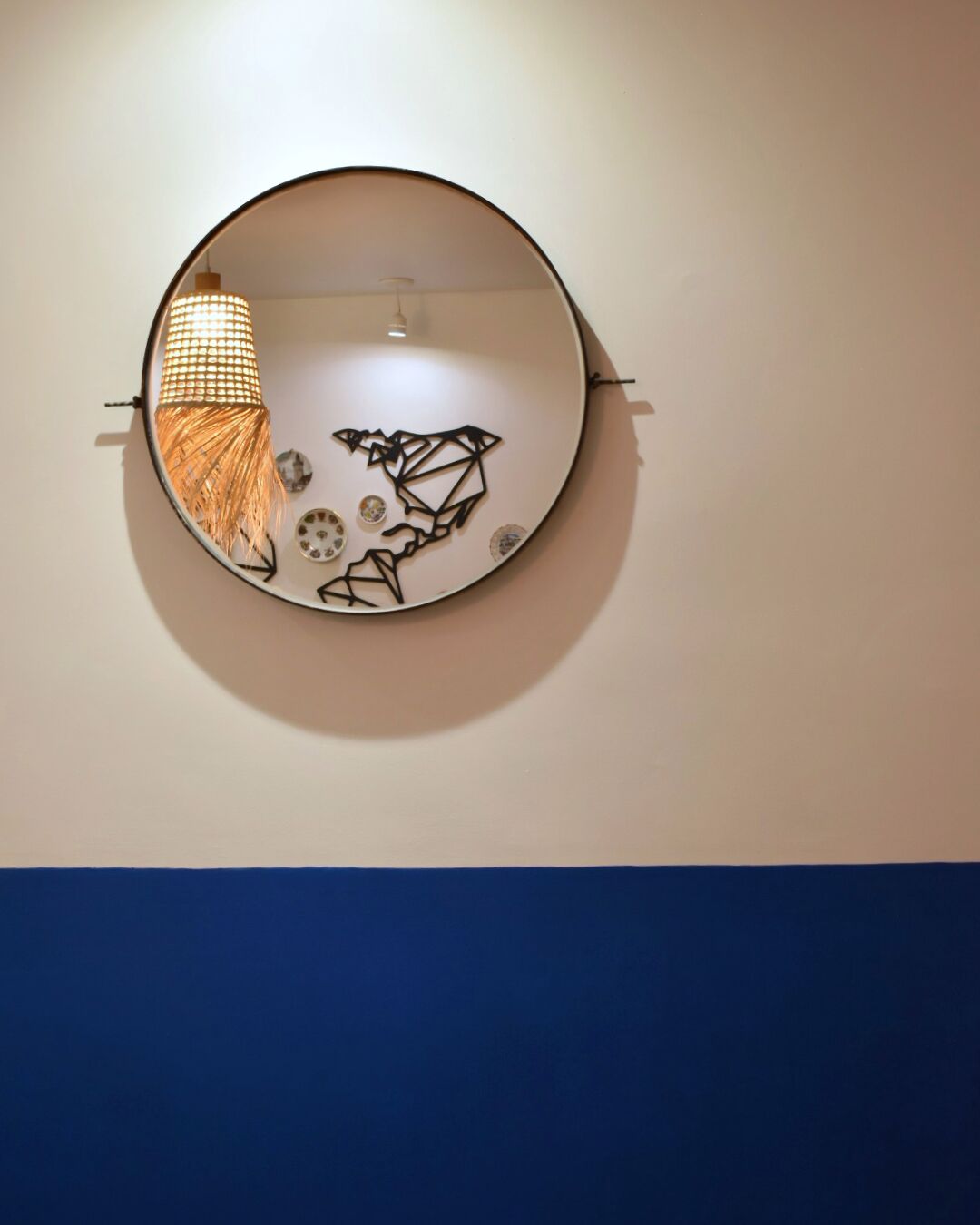A circular wall-mounted mirror with a geometric design.