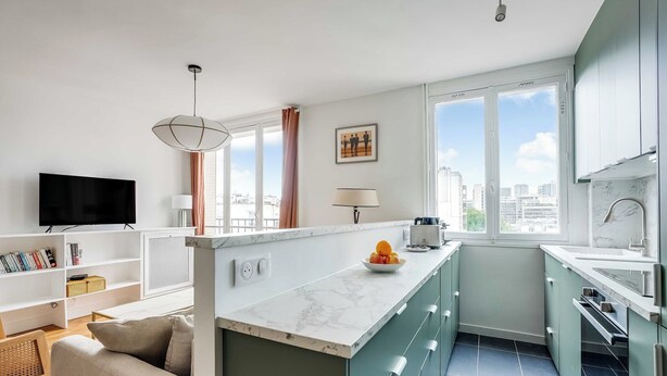 Cozinha moderna com bancada de mármore, forno embutido e janela com vista para a cidade.