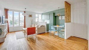Uma sala de estar moderna com sofá, mesa de jantar e área de cozinha com armários.