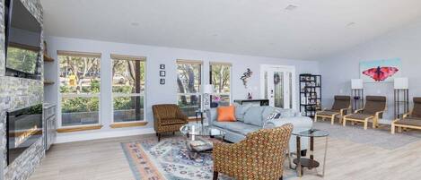 A spacious living room with a fireplace, large windows, and a variety of seating options.