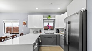 Une cuisine moderne dotée d’un grand îlot central, d’appareils électroménagers en acier inoxydable et d’une fenêtre offrant une belle vue.