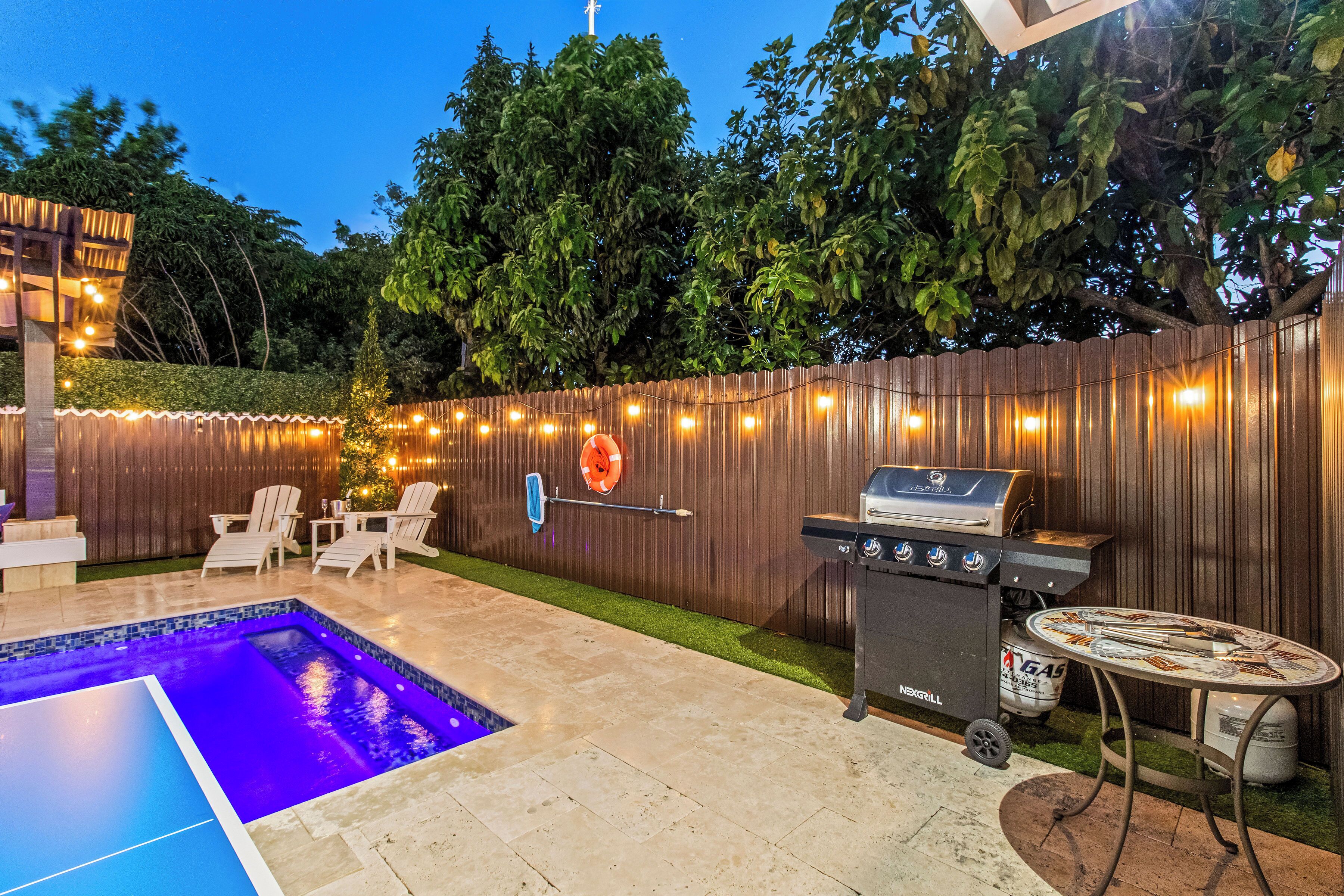 A backyard with a swimming pool, a barbecue grill, and outdoor seating.