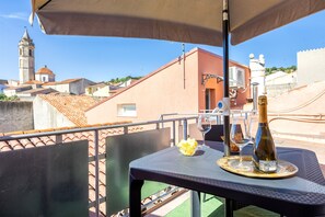 Een balkon met een tafel, een fles wijn en een glas.