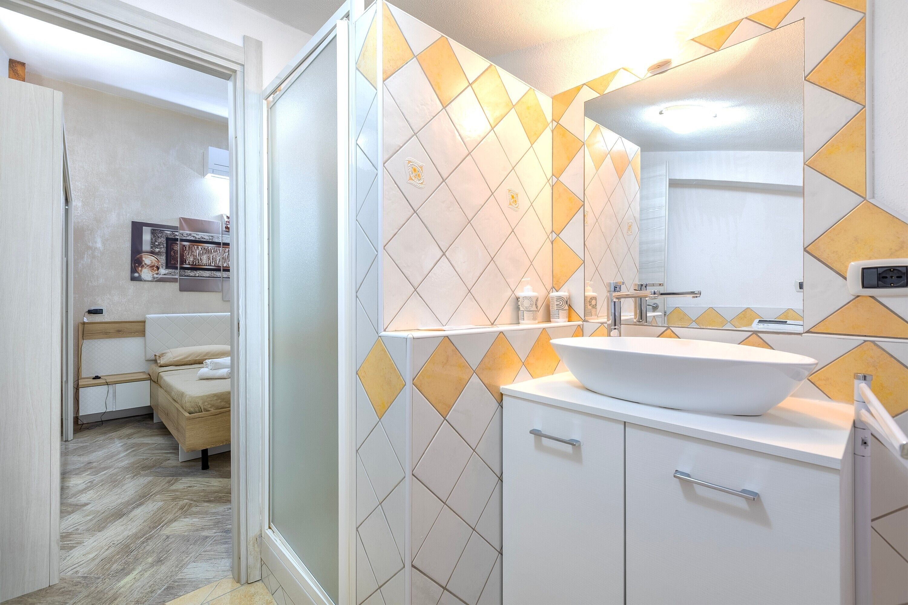 A bathroom with a white sink, mirror, and tiled walls.