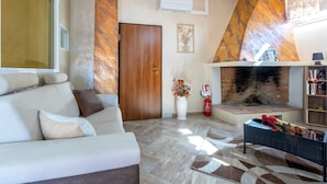 A living room with a sofa, fireplace, and a bookshelf. - Charming Penthouse in Historic Village near the Sea (Nulvi)