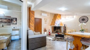 A modern living room with a sofa, a dining table, and a fireplace. - Charming Penthouse in Historic Village near the Sea (Nulvi)