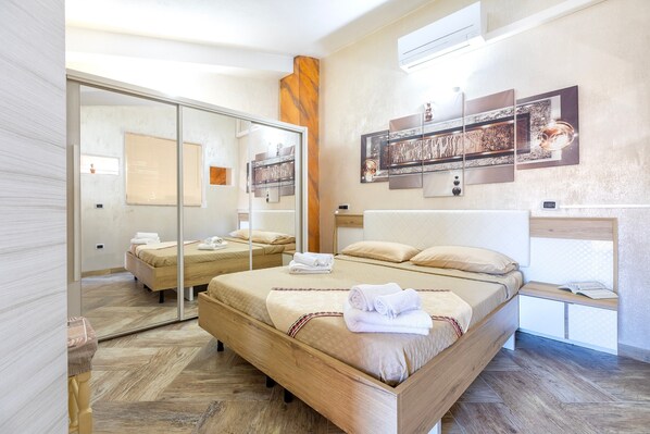 Una habitación de hotel moderna con una cama grande, un espejo, un cabecero de madera y obras de arte en la pared.
