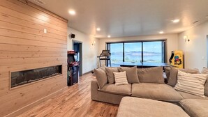 Ein Wohnzimmer mit Holzwand, einem großen Fenster, einer Couch und einem Kamin.