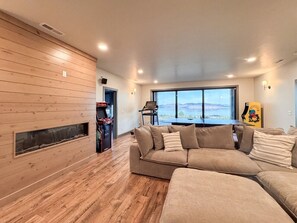 A living room with a large sectional sofa, a fireplace, and a view of the outdoors. - Bear Lake Modern Family Retreat (Garden City)
