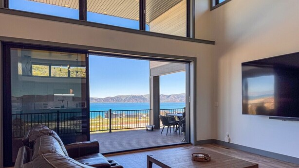 Ein modernes Wohnzimmer mit einer großen SchiebeglasTür, die auf einen Balkon mit Meerblick führt.