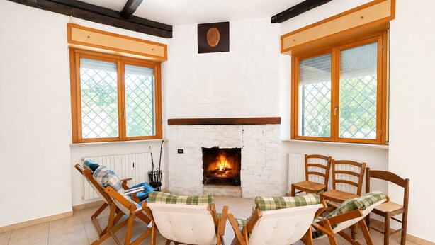 Ein Zimmer mit Kamin, Holzmöbeln und großen Fenstern.