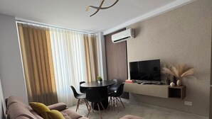 Un salon moderne avec un canapé, une table à manger et un téléviseur.