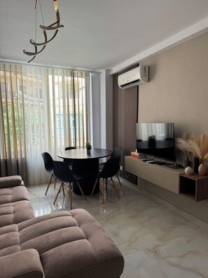 A modern living room with a sectional sofa, a dining table with chairs, a flat-screen TV, and an air conditioning unit. - * Modern Cozy Stay Near Beach, Shops & Restaurants
* Brand New Apartment (Il-Gżira)