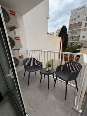 A balcony with two chairs and a small table, air conditioning units on the wall, and a view of neighboring buildings. - * Modern Cozy Stay Near Beach, Shops & Restaurants
* Brand New Apartment (Il-Gżira)