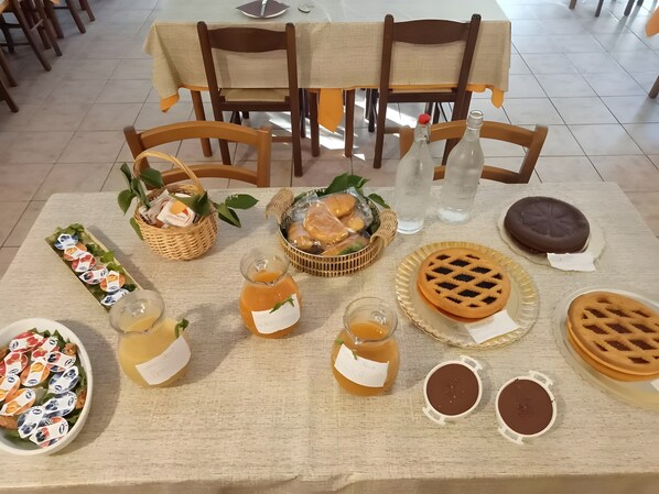 Une table dressée avec divers aliments, notamment des gaufres, une salade et une bouteille de jus.