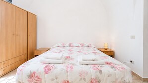 A bedroom with a bed, wooden wardrobe, bedside table, and a lamp. - Bed and Breakfast 'Casa Natura Gargano 3' (Monte Sant'Angelo)
