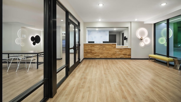 A modern office space with a reception desk, wooden flooring, and glass walls.