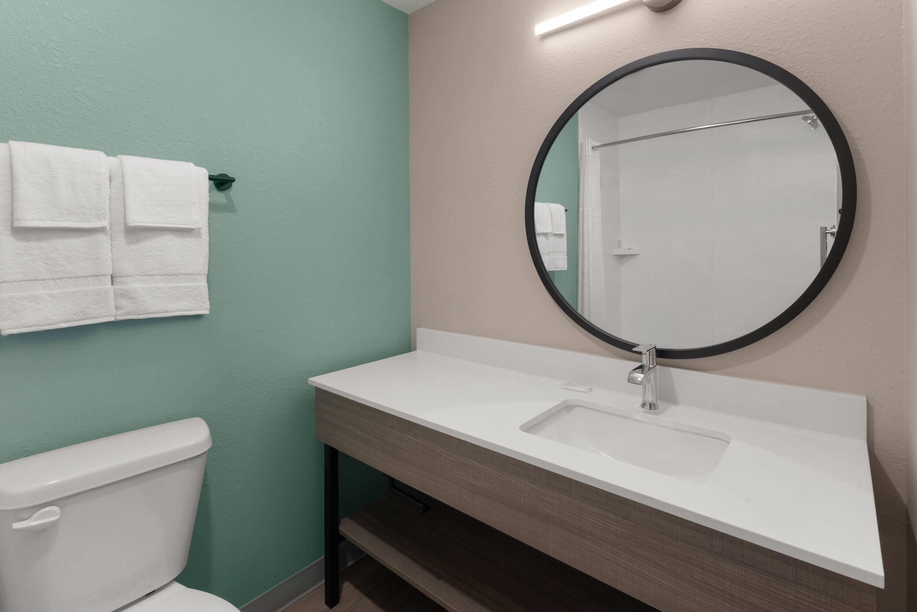 Un baño con inodoro, lavamanos y espejo.
