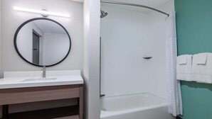 A bathroom with a round mirror, a sink, a shower, and a bathtub. - Echo Suites Extended Stay By Wyndham Savannah Pooler (Savannah)