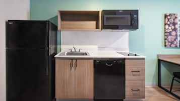 Cocina compacta con refrigerador negro, microondas, lavamanos y lavavajillas.