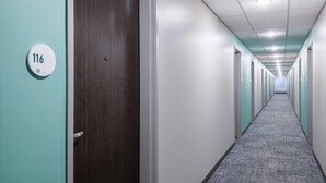 A long, narrow hallway with doors on both sides, a carpeted floor, and a ceiling with recessed lighting. - Echo Suites Extended Stay By Wyndham Savannah Pooler (Savannah)