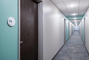 A long, narrow hallway with doors on both sides, a carpeted floor, and a ceiling with recessed lighting. - Echo Suites Extended Stay By Wyndham Savannah Pooler (Savannah)