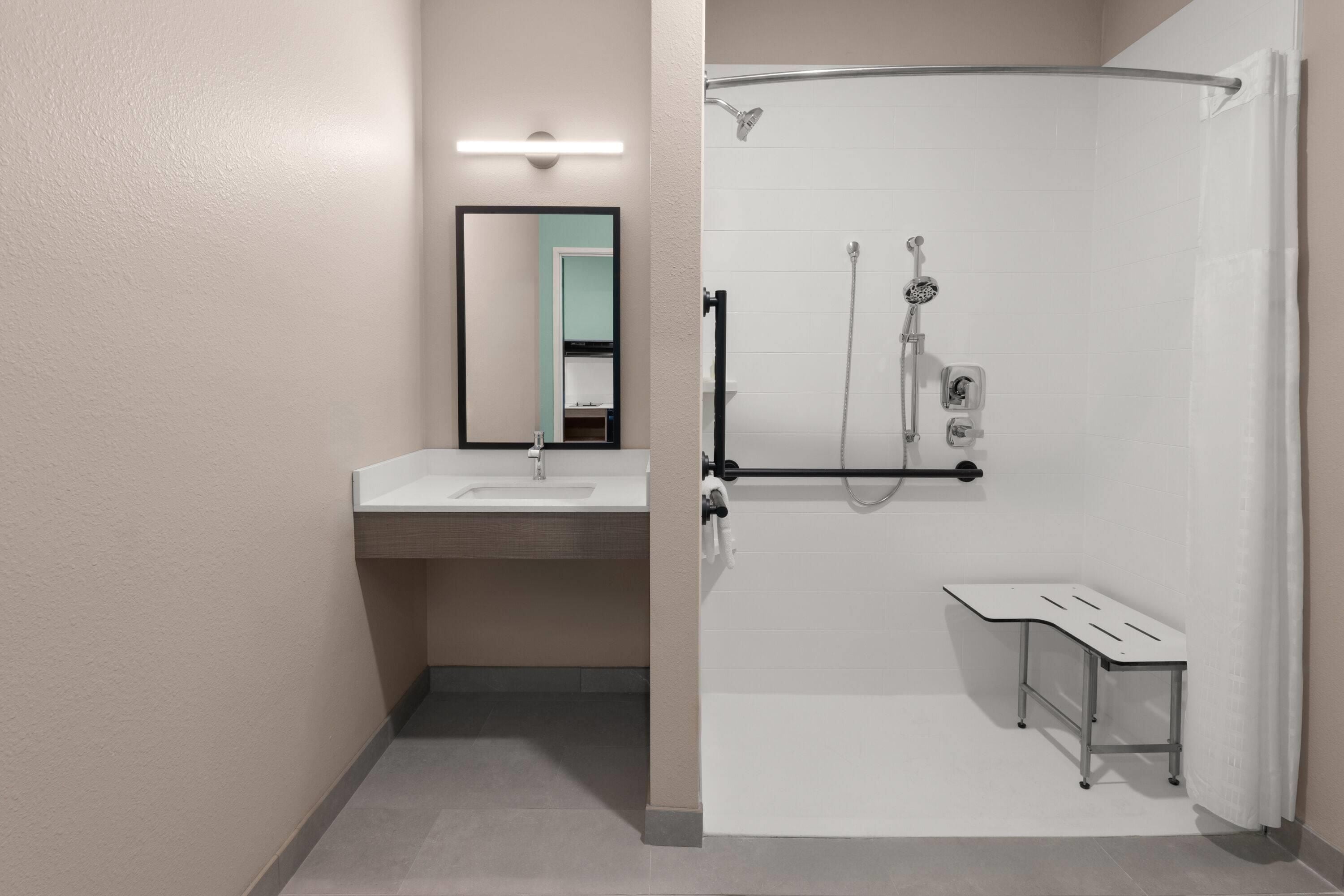 Une salle de bain moderne avec une douche, un lavabo et un miroir.