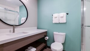 A bathroom with a white sink, a mirror, a toilet, and a shower area. - Echo Suites Extended Stay By Wyndham Savannah Pooler (Savannah)