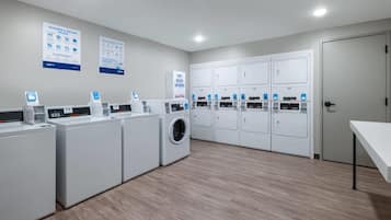 A laundry facility with multiple washing machines, dryers, and control panels.