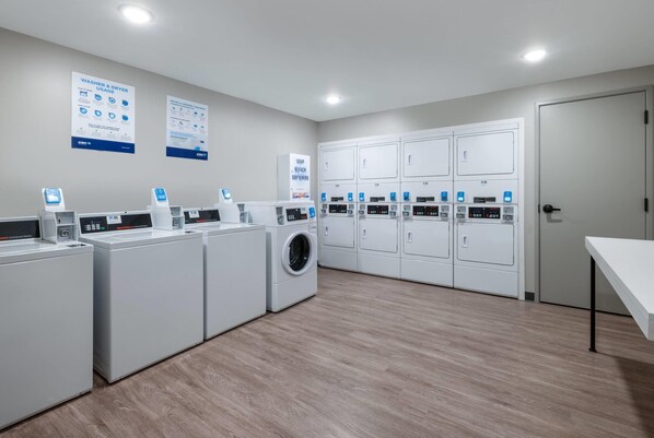 A laundry facility with multiple washing machines, dryers, and control panels. - Echo Suites Extended Stay By Wyndham Savannah Pooler (Savannah)