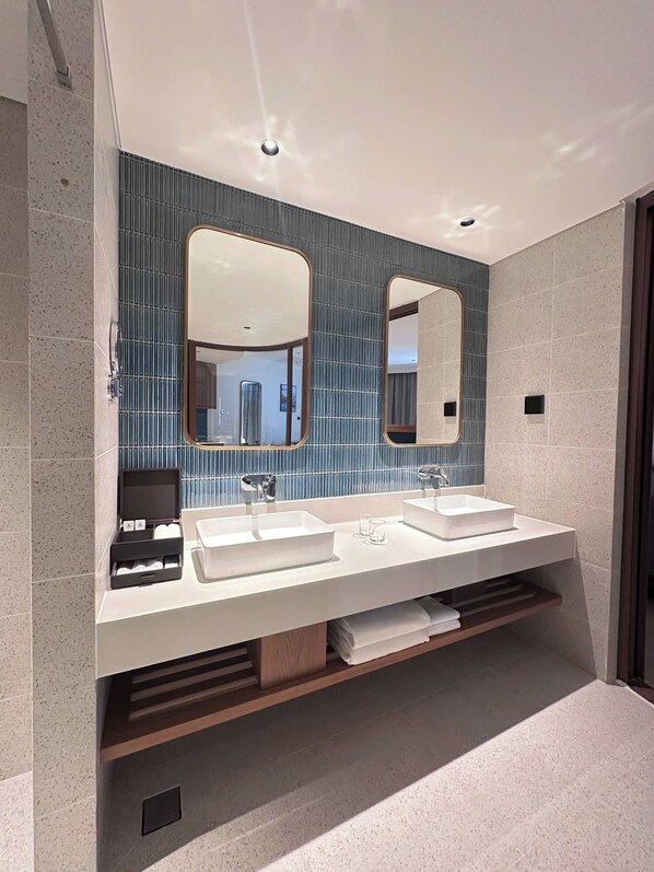 A modern bathroom with two sinks, large mirrors, and a tiled backsplash.