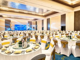 A banquet hall with round tables, white tablecloths, and chairs with gold sashes.