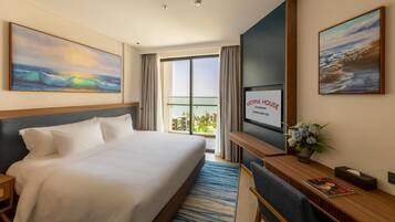 Una habitación de hotel con cama, escritorio, televisor y una ventana grande con cortinas.