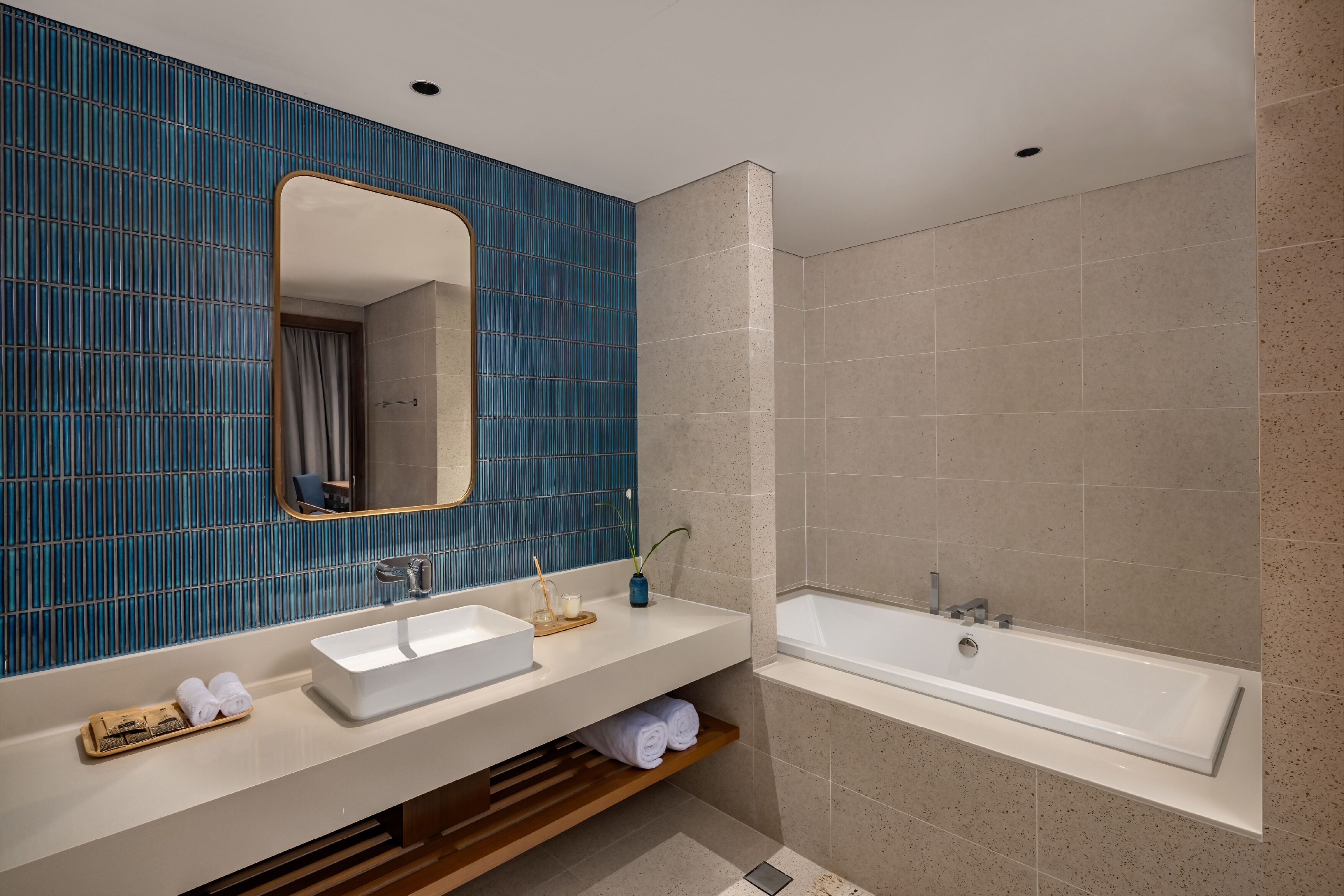 Un baño moderno con un lavamanos blanco, un espejo grande y una bañera.