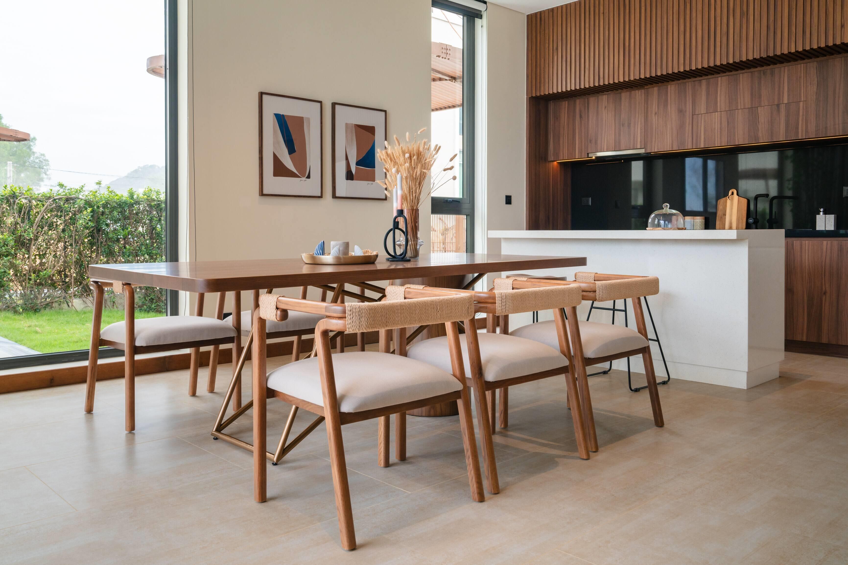 A modern kitchen with wooden cabinets, a dining area with a wooden table and chairs, and a view of the outdoors.