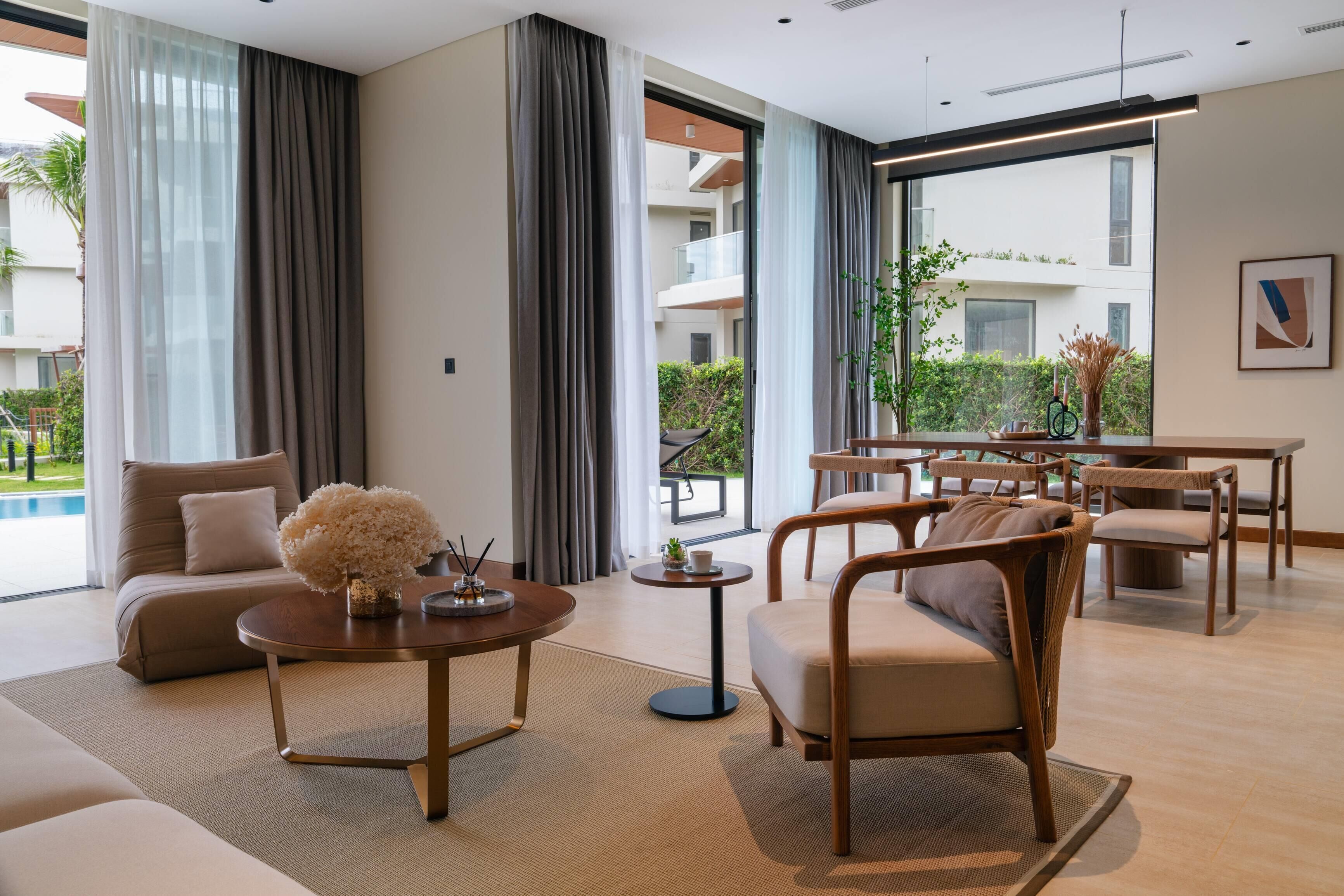 A modern hotel room with a sofa, round coffee table, and wicker chairs.