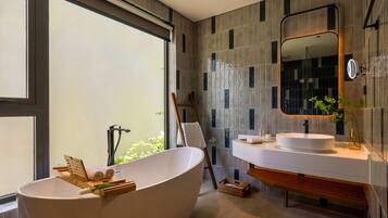 A modern bathroom with a freestanding bathtub, a large mirror, and a vanity with a sink.