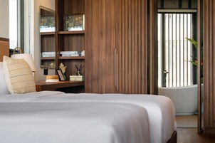 A bedroom with a large bed, wooden shelving, and a view through a window.