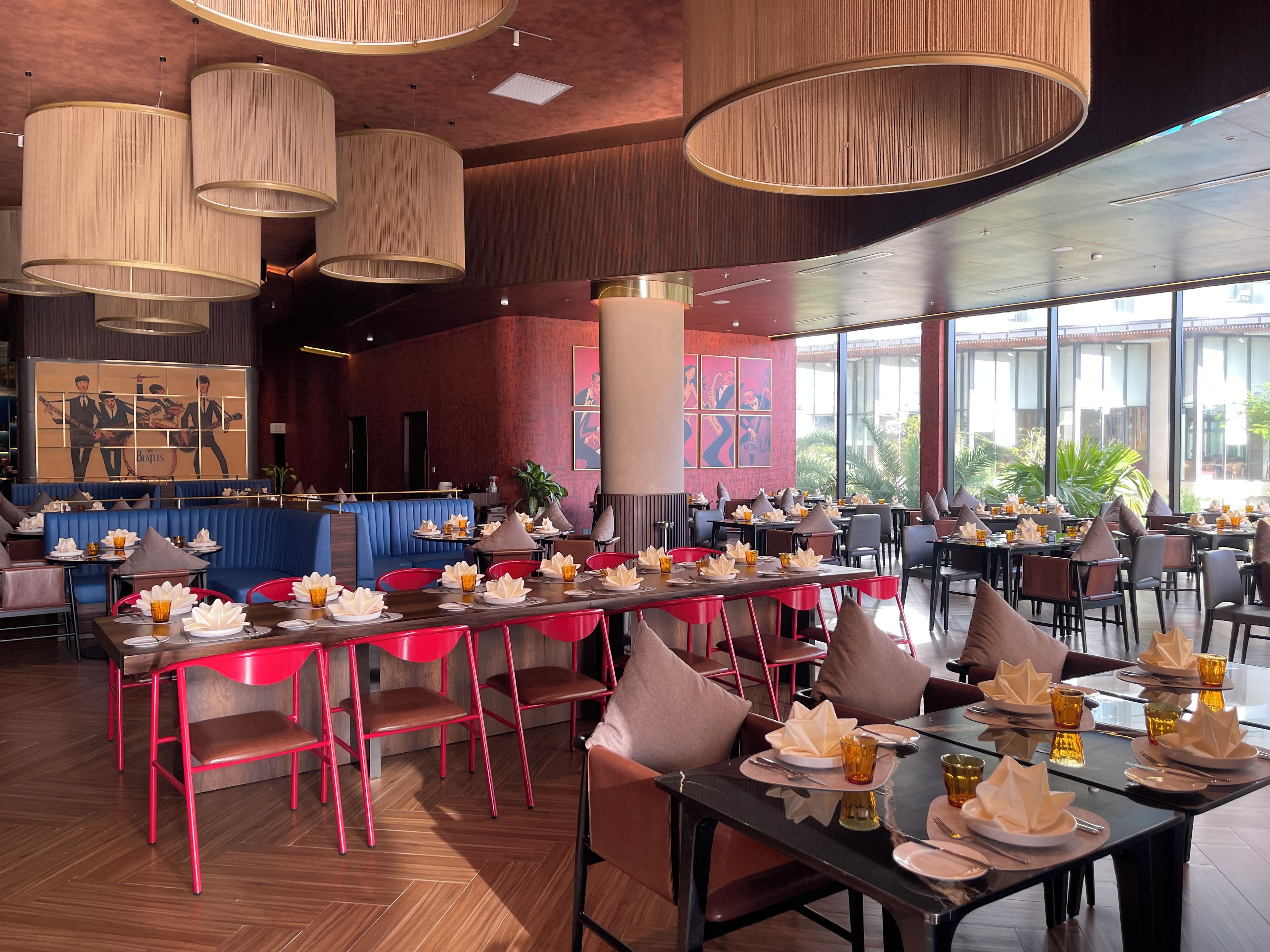 Un restaurant amb diverses taules, cadires vermelles i una zona d'seients amb banquetes blaus.