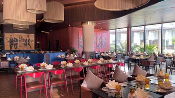 Un restaurant amb diverses taules, cadires vermelles i una zona d'seients amb banquetes blaus.