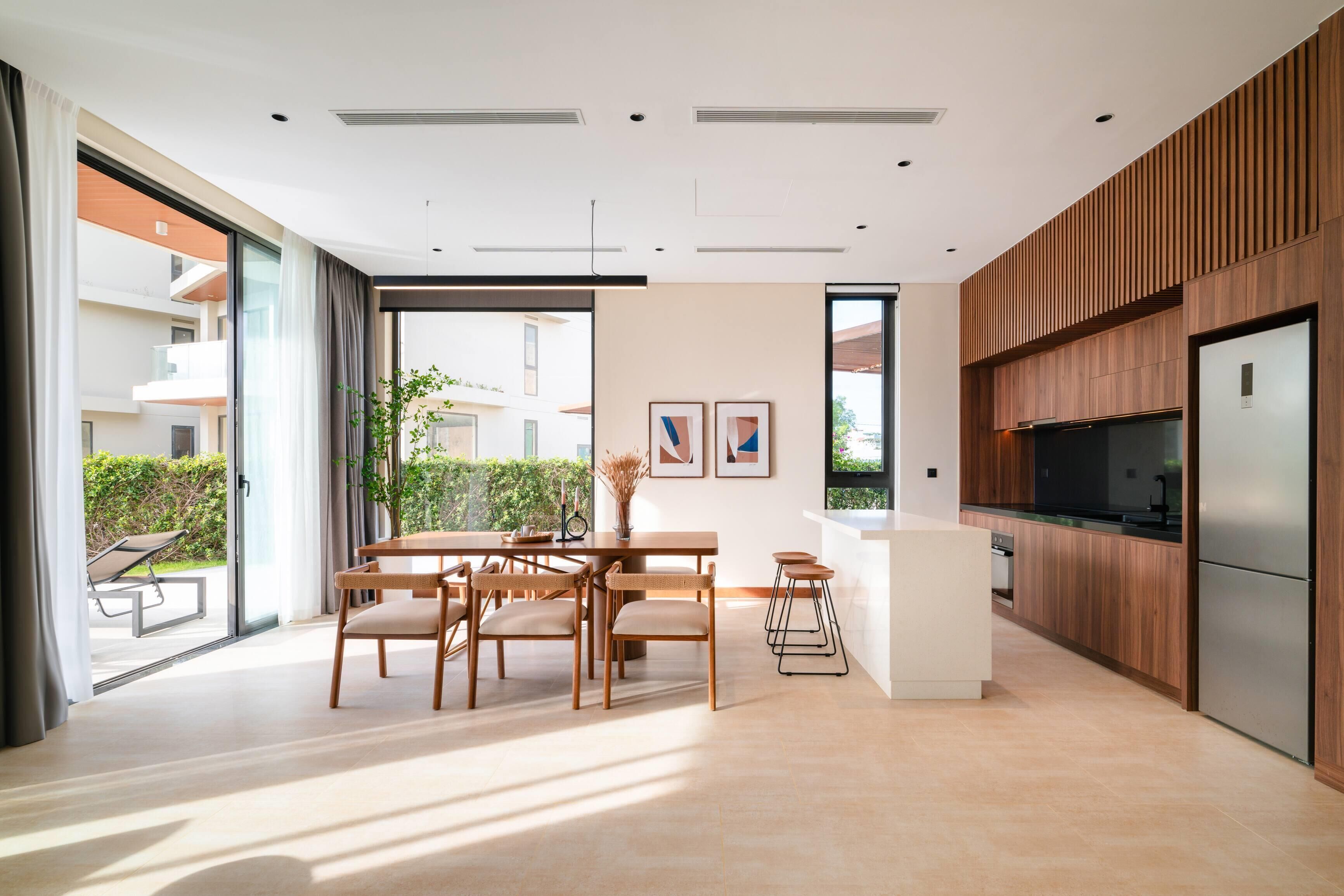 A modern kitchen with a central island, wooden cabinetry, and a stainless steel refrigerator.
