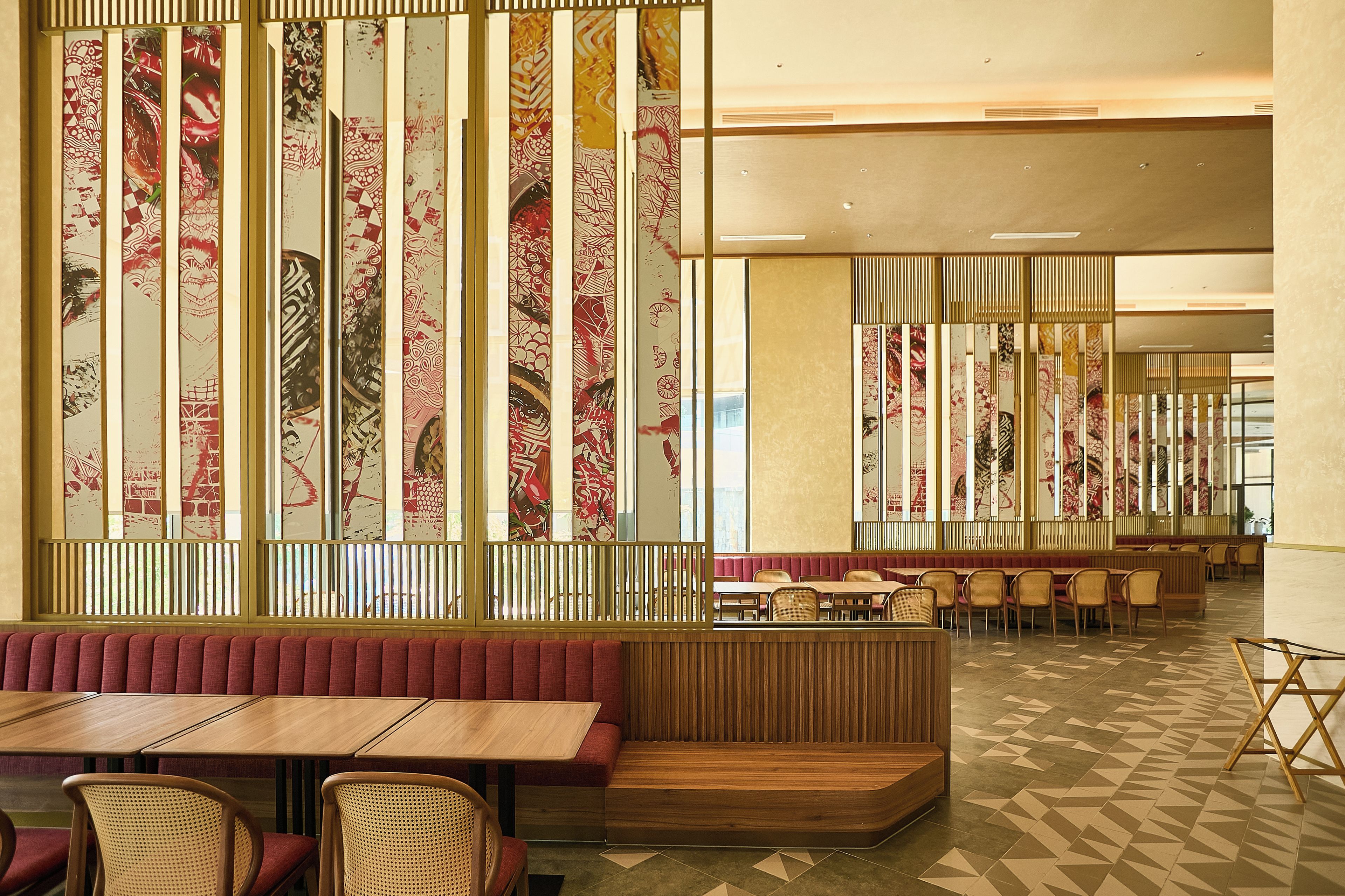 Interior de restaurante con cabinas, mesas y pared con diseño.