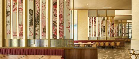 Interior de restaurante con cabinas, mesas y pared con diseño.