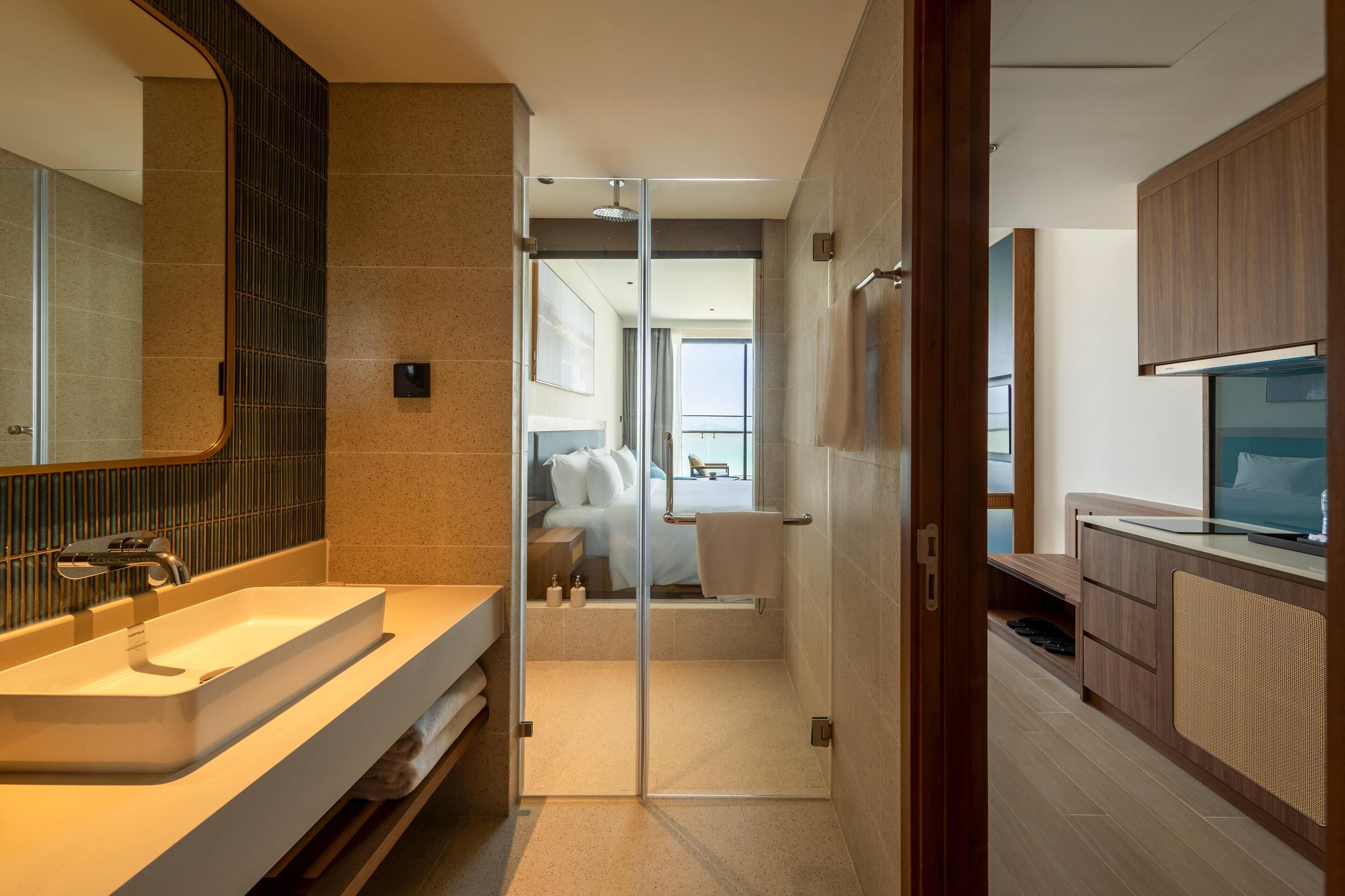 Un baño moderno con cabina de ducha de vidrio, tocador con lavamanos y televisor.