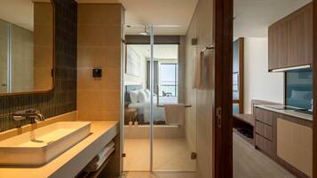 Un baño moderno con cabina de ducha de vidrio, tocador con lavamanos y televisor.