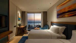 A hotel room with a bed, a desk, a chair, a TV, and a large window with a view.