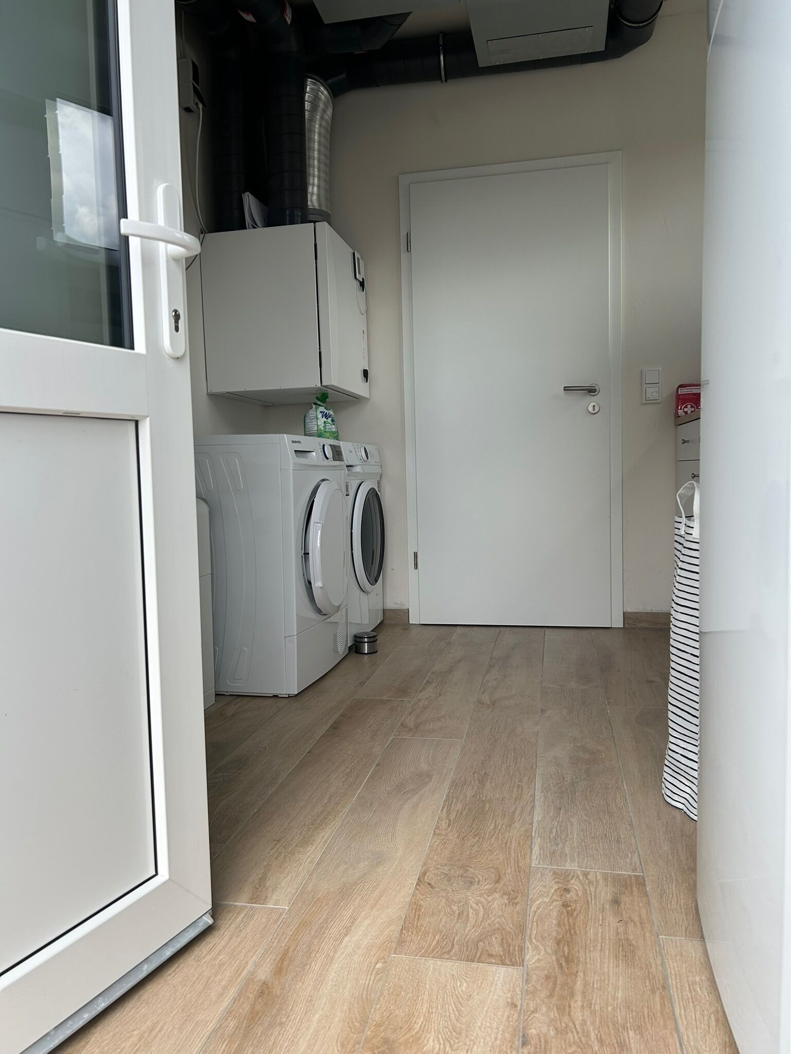 A laundry room with a washing machine, dryer, and a door leading to another room.