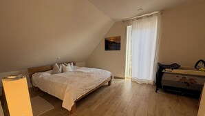 Una camera da letto con un letto, un comodino, una finestra con tende e un pavimento in legno.