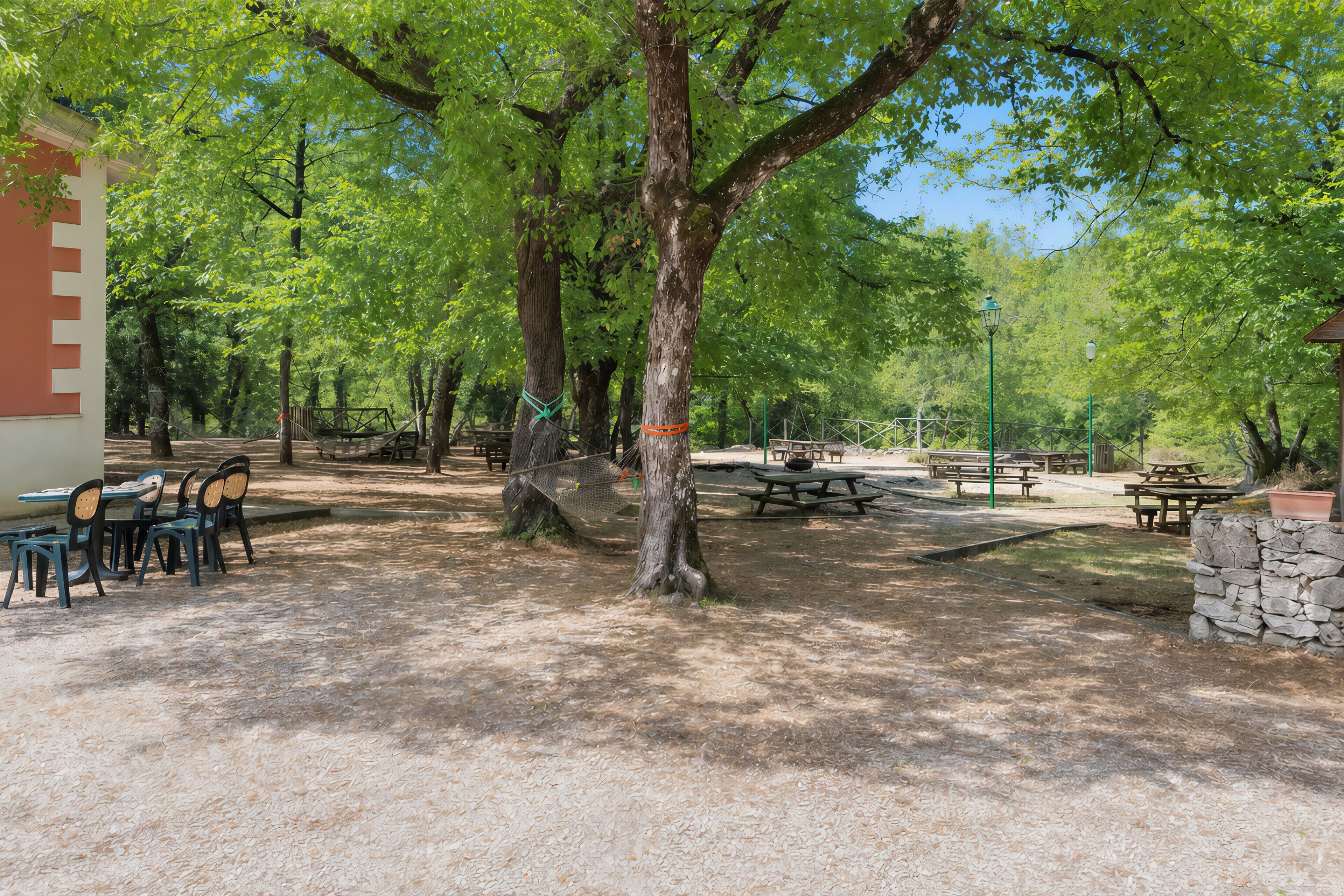 A park with picnic tables, benches, and a stone wall.