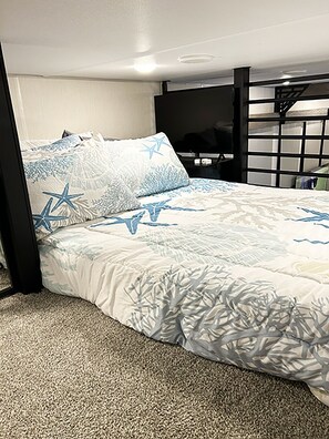 A bed with a patterned bedspread, a headboard, and a carpeted floor. - Cover RV Pad w/Large 45ft Destination RV & Outdoor Bar / Hot Tub (Bolivar Peninsula)